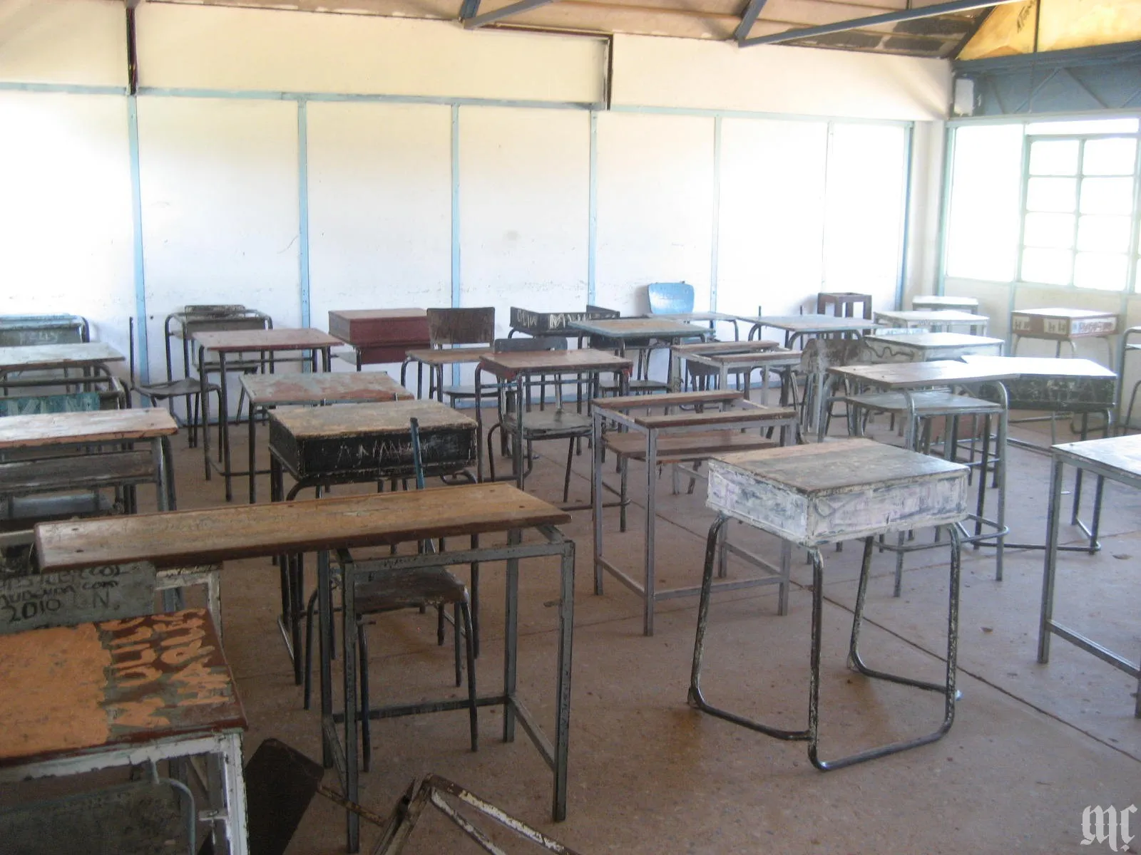 A photograph of a school classroom with desks and chairs.